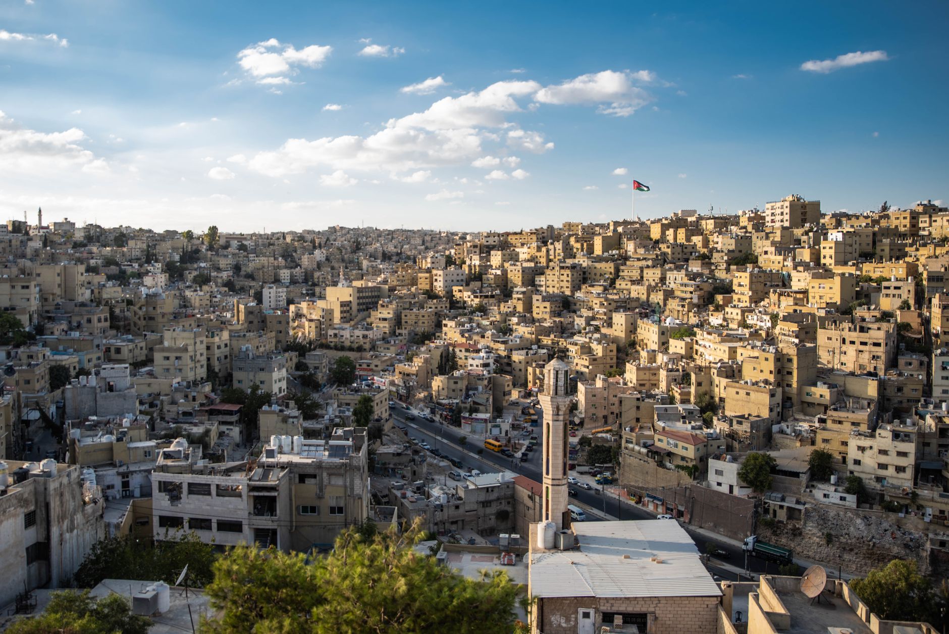 لقطة جوية لمدينة عمّان والعلم الأردني يرفرف فوقها